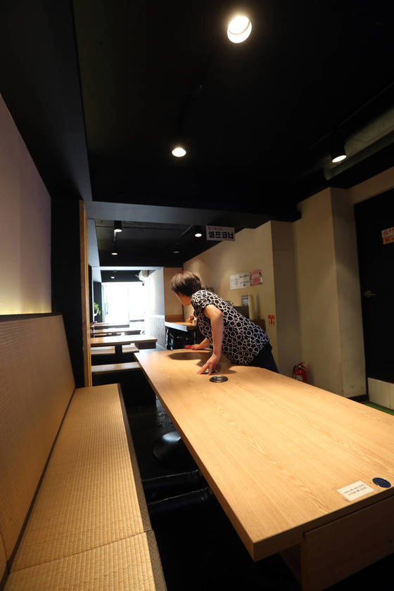 21일 서울 신촌에서 남편과 함께 일식점을 운영하고있는 가게 주인이 점심 시간에 테이블을 정리하고 있다. 낮 12시30분, 식당은 텅 비어 있다. [최정동 기자]