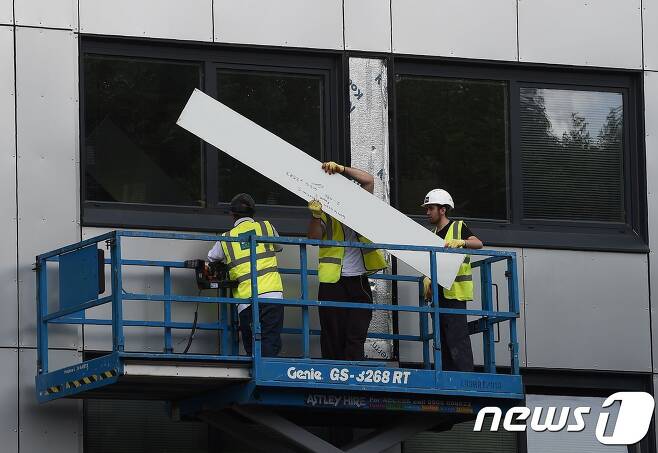 26일(현지시간) 작업부들이 영국 북부의 한 건물에서 외벽 클래딩을 제거하고 있다. © AFP=뉴스1