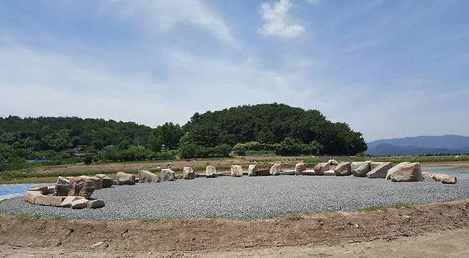경북 경주 낭산 기슭 아래 원래 윤곽대로 복원되어 늘어선 옛 신라왕릉의 석물들. 뒤로 낭산 자락과 황복사터 석탑이 보인다.