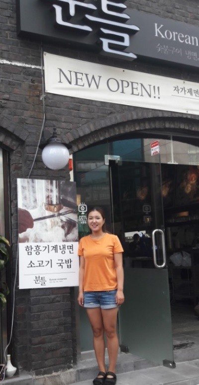 음식점 사장으로 변신한 송민지 프로가 자신이 개업한 식당 분틀 앞에서 포즈를 취했다.