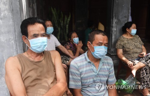 2017년 8월 11일 베트남 수도 하노이의 한 주택 앞에서 주민들이 마스크를 쓴 채 방역 작업이 끝나길 기다리고 있다. [AFP=연합뉴스]