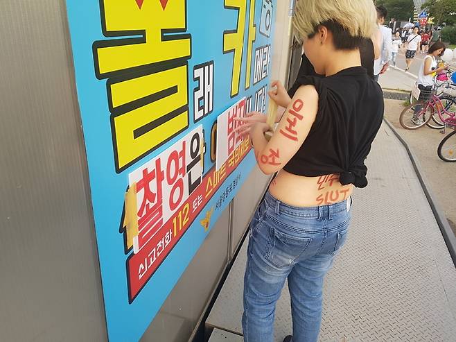 2일 여성인권단체 페미몬스터즈와 여성시민들이 서울 여의도 한강공원 공용화장실에 붙은 경찰의 경고문구(몰래카메라 신고가 예방입니다)에 ‘촬영은 범죄’라는 팻말을 붙이는 퍼포먼스를 벌이고 있다.