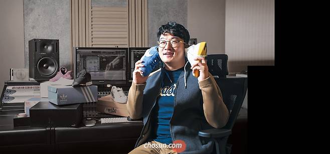 ① 이태원 음반 프로듀서가 한쪽에는 푸른색 나이키 에어 코르테즈 제품을, 다른 편엔 아디다스 퍼렐 윌리엄스 제품을 귀에 대고 포즈를 취했다. / 이신영 영상미디어 기자