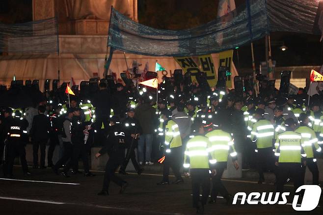 7일 오후 서울 광화문광장에서 열린 'NO WAR 평화염원 촛불문화제'에서 참가자들이 도널드 트럼프 미국 대통령의 차량이 지나가는 방향을 향해 물건을 던지자 경찰이 가림막으로 이를 막고 있다. 2017.11.7/뉴스1 © News1 신웅수 기자