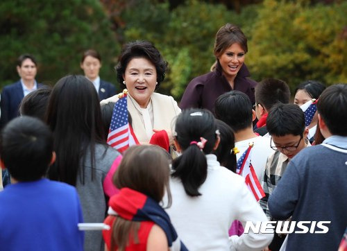 【서울=뉴시스】전신 기자 = 문재인 대통령 부인 김정숙 여사와 도널드 트럼프 미 대통령 부인 멜라니아 여사가 7일 청와대 녹지원에서 용산 남정초등학교 학생, 미8군-주한미국대사관 가족 어린이로 이뤄진 어린이 환영단에게 양국의 국기 색깔이 들어간 목도리를 걸어주고 있다. 2017.11.07. photo1006@newsis.com