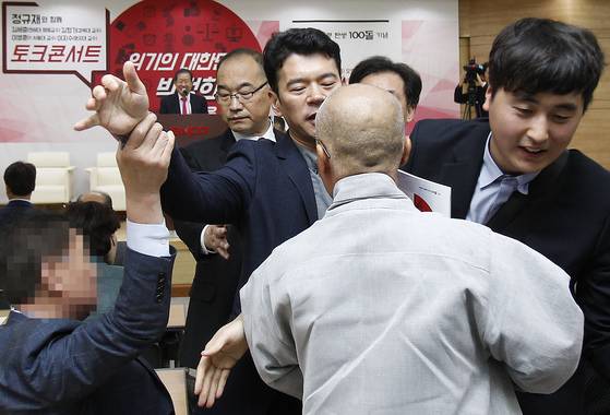 자유한국당 홍준표 대표가 10일 오후 대구 엑스코에서 열린 ‘박정희 전 대통령 탄생 100돌 기념 토크콘서트’에 참석했다. 객석에 있던 승복 차림의 한 남성이 무대에 올라 축사하던 홍 대표를 향해 고함을 지르자 주변 관계자들이 남성을 제지하고 있다. 이 광경을 지켜보는 홍 대표는 미소를 짓고 있다. 프리랜서 공정식