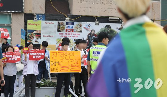 23일 오후 부산 해운대구 구남로 문화광장에서 열린 성 소수자 문화행사인 '부산 퀴어문화축제'에 참가한 참가자가 반대 단체 회원들의 손팻말을 바라보고 있다. 2017.9.23/뉴스1  <저작권자 © 뉴스1코리아, 무단전재 및 재배포 금지>