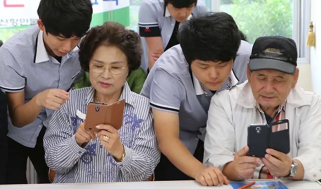 지난 2014년 부산항만물류고 학생들이 부산 남구노인복지관에서 어르신들을 대상으로 스마트폰 사용법을 설명하는 모습. 전문가들은 노인 차별을 해소하려면 모든 세대를 아우르는 사회적 분위기가 마련돼야 한다고 강조한다. [중앙포토]