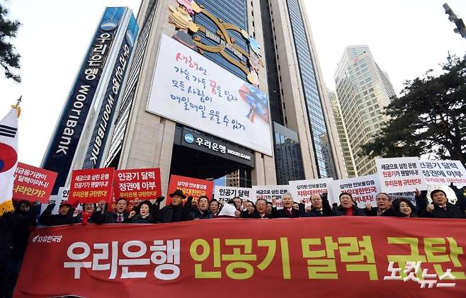 자유한국당 중앙직능위원회 위원들이 3일 오후 서울 중구 우리은행 본점 앞에서 우리은행의 탁상달력에 북한 인공기가 등장한 것을 규탄하는 기자회견을 갖고 있다.  해당 달력 1월 삽화엔 광화문 촛불집회 현장이 묘사돼 있고, 10월엔 태극기와 인공기가 걸려있는 통일나무 주위에서 아이들이 손을 맞잡은 모습이 그려져 있다.