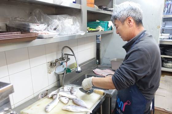 주인 채성수씨가 구이용으로 쓸 백조기를 다듬고 있다.