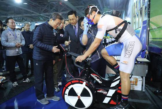 문재인 대통령이 진천선수촌 웨이트 트레이닝센터에서 사이클 국가대표 선수가 무산소 파워 훈련용 자전거(와트바이크)로 훈련하는 모습을 참관하고 있다. [연합뉴스]
