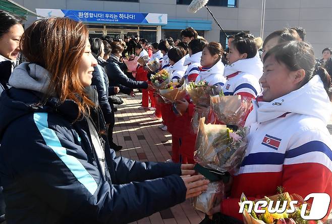 대한민국 여자 아이스하키 선수단이 평창동계올림픽에서 단일팀으로 함께 뛸 북한 선수단에게 25일 충북 진천군 진천 국가대표선수촌 빙상장 앞에서 처음으로 만나 꽃다발을 건네주며 환영하고 있다..2018.1.25/뉴스1 © News1 사진공동취재단