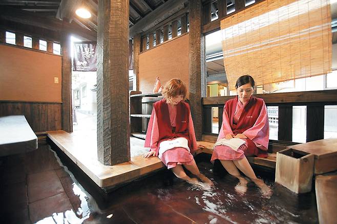 야마노유 온천료칸의 족욕탕에서 일본 전통 복장인 유카타를 입고 족욕을 하는 일본인 관광객들. / 구로카와 온천마을 료칸조합