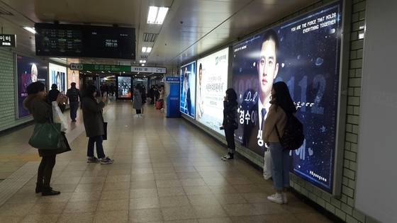 지난 21일 서울 삼성역에 걸린 아이돌 광고판 앞에서 소녀팬들이 인증샷을 남기고 있다. 임선영 기자