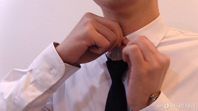 유승목 기자(27)가 와이셔츠 목 부분의 까끌까끌한 소재에 불편함을 호소하며 넥타이를 풀고 있다./사진=이상봉 기자