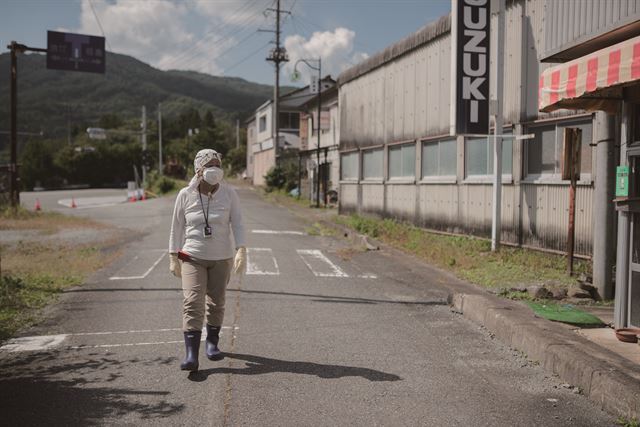 2017년 9월 후쿠시마 사고 피난민인 칸노 미즈에 씨가 후쿠시마현 나미에 지역의 피난구역인 쓰시마 거리를 걷고 있다. 그린피스 제공