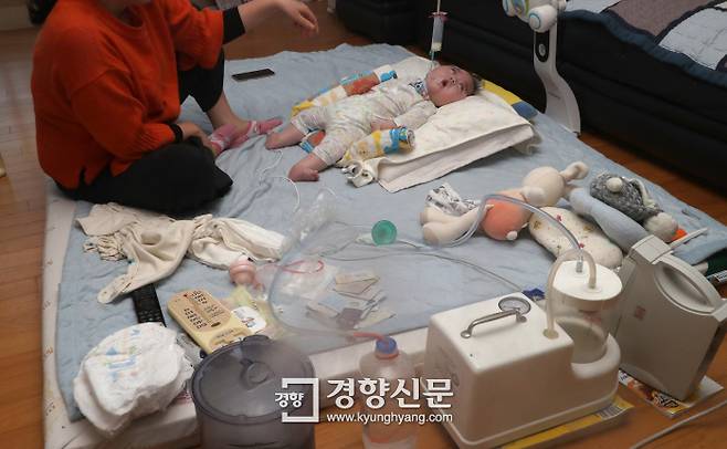 지난 2월1일 저산소성 허혈성 뇌병증을 앓고 있는 생후 10개월 된 본재의 어머니 허아현씨(가명)가 본재 곁을 지키고 있다. 방 한쪽에는 본재를 치료하기 위한 의료기기와 각종 약이 놓여 있다. 권도현 기자