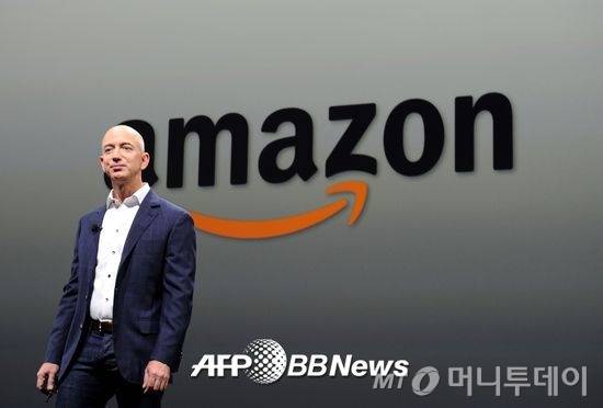제프 베저스 아마존(amazon) CEO가 회사 로고 앞에 서 있다. 2000년부터 아마존은 현재의 로고를 쓰고 있다. A부터 Z까지 모든 것을 판다는 것과 고객의 웃음을 나타낸다. /AFPBBNews=뉴스1