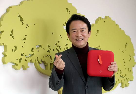 남경필 경기지사가 지난달 29일 경기도청 집무실 벽에 설치된 연리지 배경 앞에서 손가락으로 하트 모양을 만들며 포즈를 취하고 있다. 왼손에 경기도에 있는 중소기업이 만든 시계 겸 긴급구호장비 세트를 들고 있다. 최승식 기자