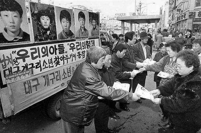 실종된 개구리소년 가족과 개구리소년찾기 후원회 회원들이 서울 종로구 종로5가 동대문시장 입구에서 소년들의 얼굴사진이 들어있는 유인물을 나눠주고 있다. <한겨레> 자료 사진.