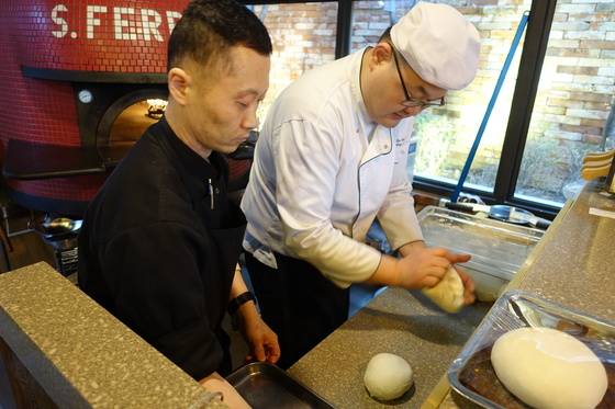 1차 발효를 마친 빵 반죽을 오븐에서 2차 발효하기 전에 치대고 있다.