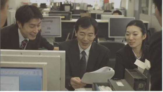 도쿄도가 제작한 ‘암 치료와 일 병행’ 캠페인 비디오의 한 장면. 치료를 받은 동료(가운데)가 완치됐다는 결과지를 받자 기뻐하고 있다. [윤설영 특파원]