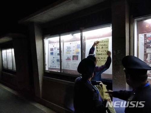 【서울=뉴시스】중국 베이징 대학측이 20여년 전 이 대학에서 발생한 성폭행 및 피해 여학생의 자살에 대한 진상 규명을 요구하는 여학생에게 침묵을 강요하는 위협을 한 것을 비난하는 대자보를 떼어내고 있다. <사진 출처 : supchina.com> 2018.4.25