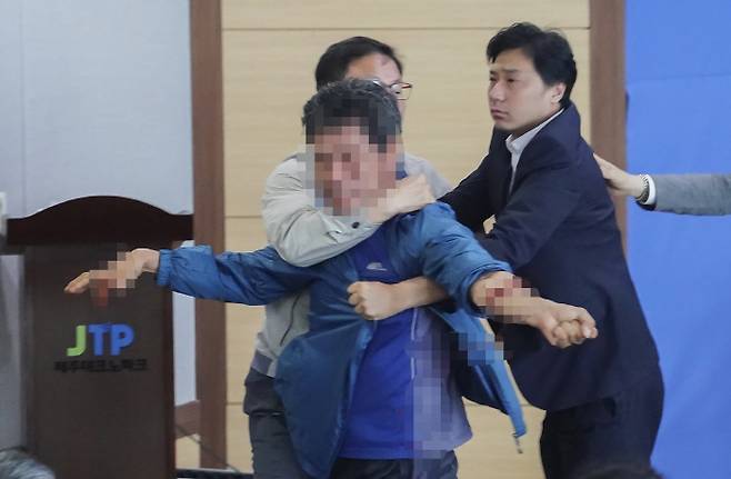 14일 오후 제주시 벤처마루에서 열린 ‘2018 지방선거 제주도지사 후보 원포인트 토론회’에서 제주 제2공항 반대 활동을 했던 김모씨가 무대에 올라가 원희룡 예비후보를 폭행한 뒤 자해하다 제지 당하고 있다. 원희룡 캠프 제공=연합뉴스