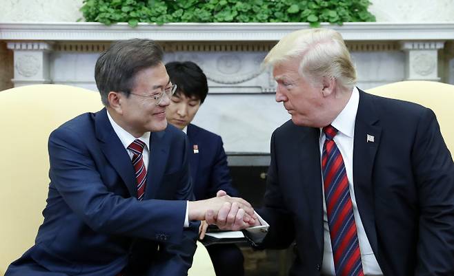 문재인 대통령과 도널드 트럼프 미국 대통령이 22일 오전한국 시간) 백악관 오벌오피스에서 열린 한·미 정상 단독회담에서 손을 잡고 얘기를 나누고 있다. 2018.5.23 /연합뉴스