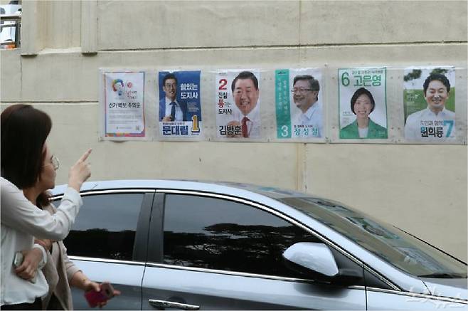 제주지사 후보들의 선거벽보가 붙여진 곳을 시민들이 지나가고 있다. (사진=이인 기자)