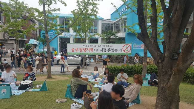 서울 마포구 연남동 경의선숲길에서 시민이 돗자리를 편 채 휴식을 즐기고 있다. 돗자리마다 맥주가 담긴 일회용컵이 눈에 띈다. ‘음주청정지역’을 안내하는 표지판이 무색하다. 이원율 기자/yul@heraldcorp.com