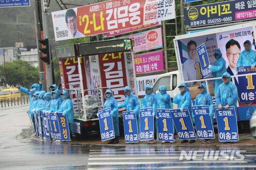 【포항=뉴시스】강진구 기자 = 6·13전국동시지방선거 경북도의회 포항시 제4선거구(장량동)에 출마한 더불어민주당 이송교 후보는 11일 오전 장량동 삼도W사거리에서 선거운동원들에게 우의를 입히고 차량 앞에 도열해 놓고 정작 자신은 차안에서 인사에 나서 눈살을 찌푸리게 했다.더욱이 상대 후보가 선점해 놓은 자리에 끼어들기해 ‘황제 선거운동’이란 비난을 샀다.2018.06.11.  dr.kang@newsis.com