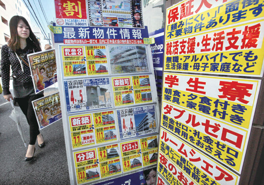부동산 중개업소의 주택 임대·매매 광고가 내걸린 일본 도쿄 거리를 한 시민이 지나가고 있다. 일본 부동산 시장은 1990년대 초반부터 20년 넘게 불황을 겪다 최근 회복세를 보이고 있다. /블룸버그 제공