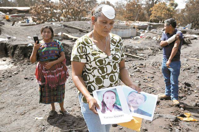 12일 과테말라 에스쿠인틀라 산미겔 마을에서 한 여성이 남편과 두 딸의 사진을 보여주며 침통한 표정을 짓고 있다. 로이터 연합뉴스