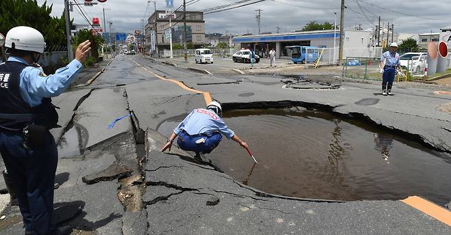 18일 오사카 현 다카쓰키시에서 발생한 지진으로 인한 도로 파손 사고를 점검하고 있다. 일본 서부를 강타한 이 지진은 50명 이상의 부상자를 냈다. [EPA=연합뉴스]
