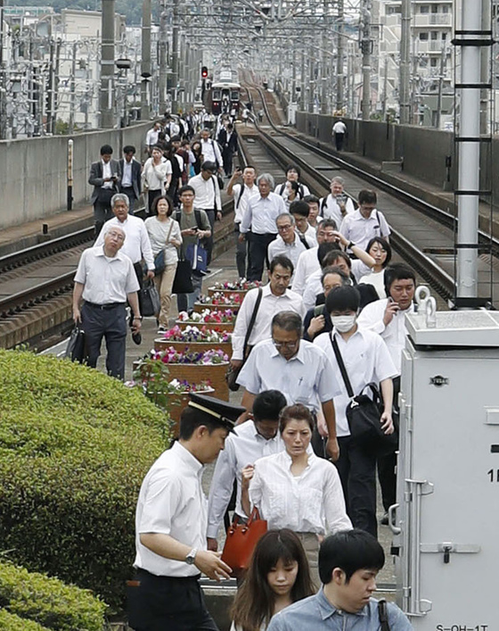 오사카 지역 강진으로 이케다에서 열차 운행이 중단되자 승객들이 걸어서 이동하고 있다.[교도=연합뉴스]