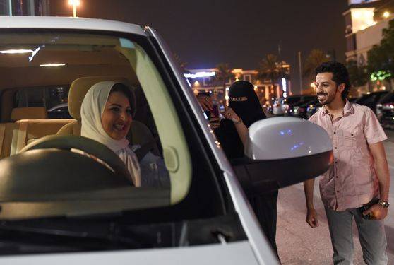 사우디 한 여성과 남성이 24일(현지시간) 리디야 시내를 처음으로 운전한 사마르 알 모겐을 응원하고 있다. [AFP=연합뉴스]
