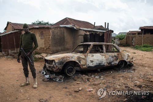 지난달 27일 나이지리아 플라토주에서 유목민 풀라니족의 공격으로 타버린 차 옆에 보안군이 서 있다. [AFP=연합뉴스 자료사진]
