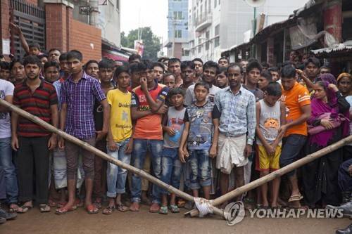 방글라데시 사람들이 지난 2017년 7월 폭발 사고가 난 의류공장 앞에 서 있다. [EPA=연합뉴스 자료사진]