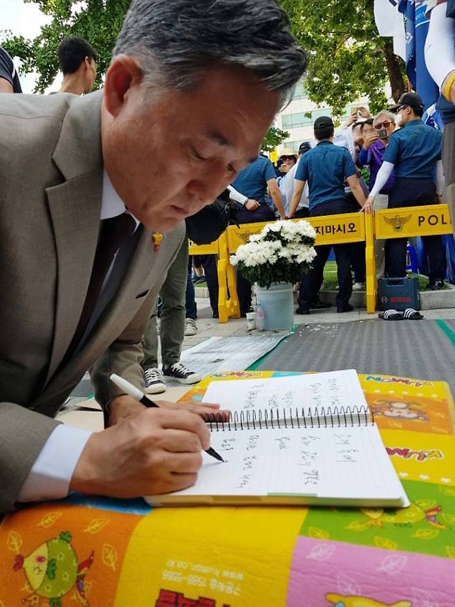 표창원 더불어민주당 의원이 같은 당 박주민 의원과 함께 4일 오후 서울 중구 대한문 앞에 마련된 금속노조 쌍용차지부의 노조원 분향소를 방문해 참배 후 방명록을 작성하고 있다. 표 의원은 "고개 숙여 삼가 고인의 명복을 빕니다. 다시는 불행한 희생이 없도록 최선의 노력을 다하겠습니다."라고 글을 남겼다. [연합뉴스]
