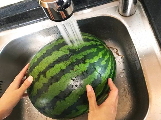 흐르는 물에서 수박을 돌려가며 베이킹소다를 잘 씻어낸다.