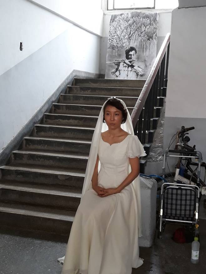 지난 21일 광주 광천동 시민아파트에서 현대무용가 나은영이 5·18 시민군 대변인 윤상원과 영혼결혼식을 올린 박기순의 역을 맡아 퍼포먼스를 하고 있다. 이 아파트 나동 계단에 놓인 그림 속의 윤상원이 웨딩드레스를 입은 신부의 모습을 쳐다보는 것처럼 느껴진다. 정대하 기자