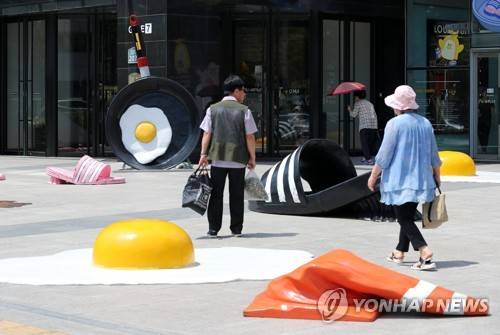 더위에 지친다 (대구=연합뉴스) 김준범 기자 = 찜통더위가 이어진 23일 오후 현대백화점 대구점 앞에서 시민들이 더위에 익은 달걀프라이와 녹아내린 슬리퍼 조형물 사이를 지나가고 있다. 2018.7.23      psykims@yna.co.kr
