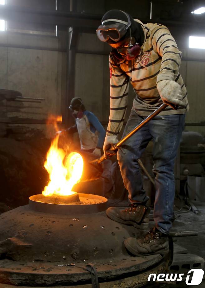 29일 경북 구미시 고아읍 사랑채 가마솥공장에서 한 직원이 살이 타들어가는 무더위와 싸우며 지름 1m 크기의 대형 무쇠 가마솥 거푸집에 1500도에서 선철을 녹여 만든 쇳물을 붓고 있다.2018.7.29/뉴스1 © News1 정우용 기자