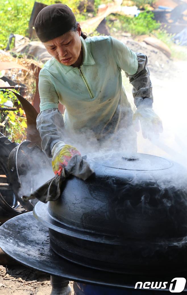 29일 경북 구미시 고아읍 사랑채 가마솥공장에서 박경화(54)씨가 식용유를 묻힌 기름천으로 가마솥 길들이기를 하고 있다. 토치로 식힌 가마솥을 다시 가열하면서 기름천으로 길들이는 작업은 가마솥에 화장을 하는 것과 같다.2018.7.29/뉴스1 © News1 정우용 기자