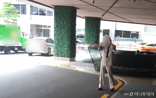 한 호텔 안내직원이 모자를 벗고 땀방울을 훔친 뒤 다시 옷매무새를 정돈하고 있다./사진=남형도 기자