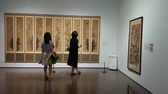 갤러리현대 전시장에서 관객이 꽃과 새, 괴석을 그린 10폭 병풍을 감상하고 있다.