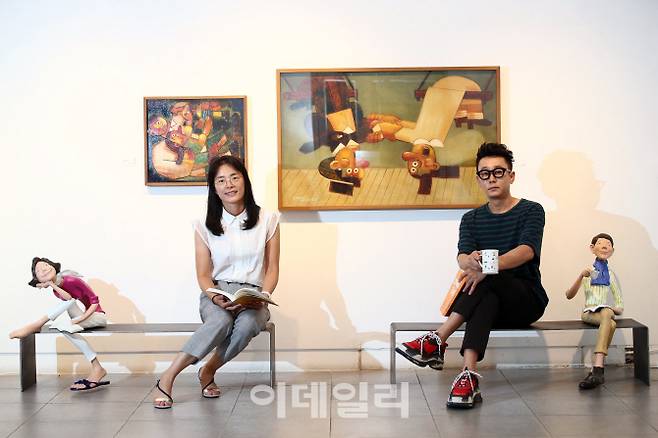 조각가 김경민(왼쪽)과 화가 문형태가 서울 종로구 인사동 선화랑서 연 2인전 ‘기분좋은 기억’에 걸고 세운 자신들의 작품 곁에 앉았다. 두 작가 좌우로 놓인 작품은 김경민의 조각 ‘만남 그 후’(2015). 뒤로는 문형태의 그림 ‘가족’(2018)과 ‘공중그네’(2016)가 보인다(사진=노진환 기자).
