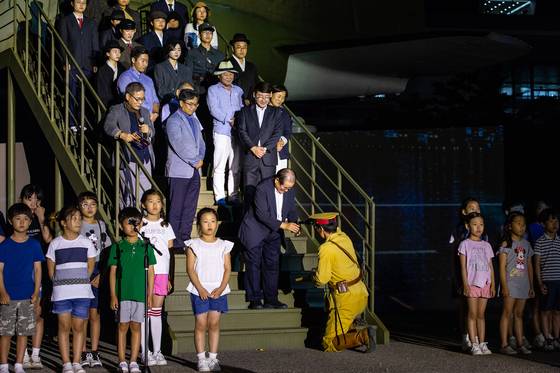 일본군 역할의 배우가 관계자에게 술을 따르고 있다. 이는 1946년 착륙 당시 경비사령관 시부자와 대좌와 우에다 히데오 소좌 등이 기린맥주와 일본 술 사케를 들고 미군과 광복군 정진대를 찾아 항복의 예를 갖추며 술을 따랐던 상황을 재연한 것이다. [사진 3·1운동 100주년 서울시기념사업사무국]