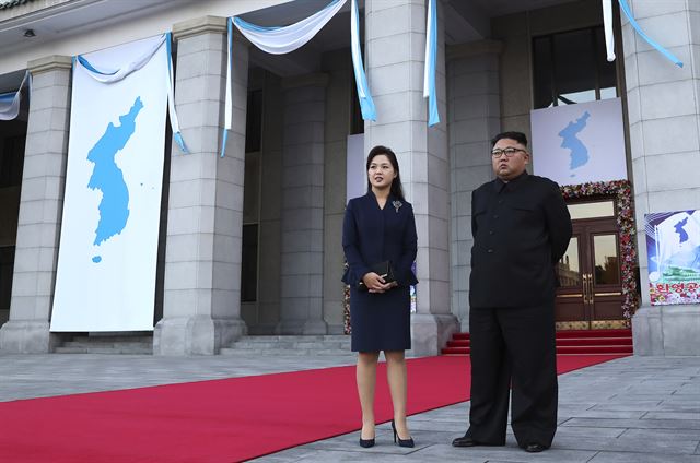 18일 저녁 삼지연 관현악단의 환영공연이 열린 평양대극장 앞에서 김정은 국무위원장과 리설주 여사가 문 대통령 내외를 기다리고 있다. 대형 걸개그림 형태의 한반도기가 극장 외벽에 걸려 있다.